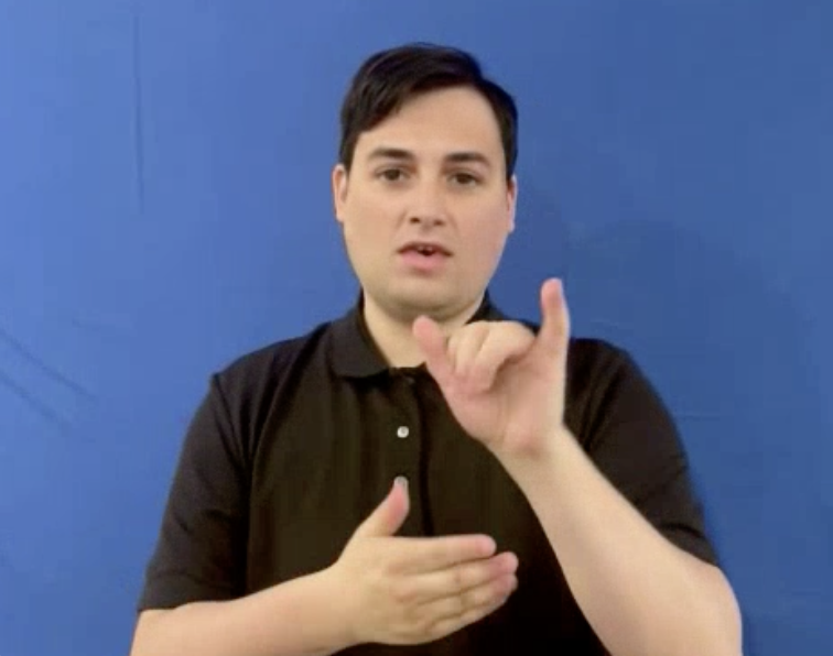 Image of an avatar that appears as a young man from the waist up who is signing the word "that." He has short black hair and is wearing a black polo shirt. The background is sky blue.